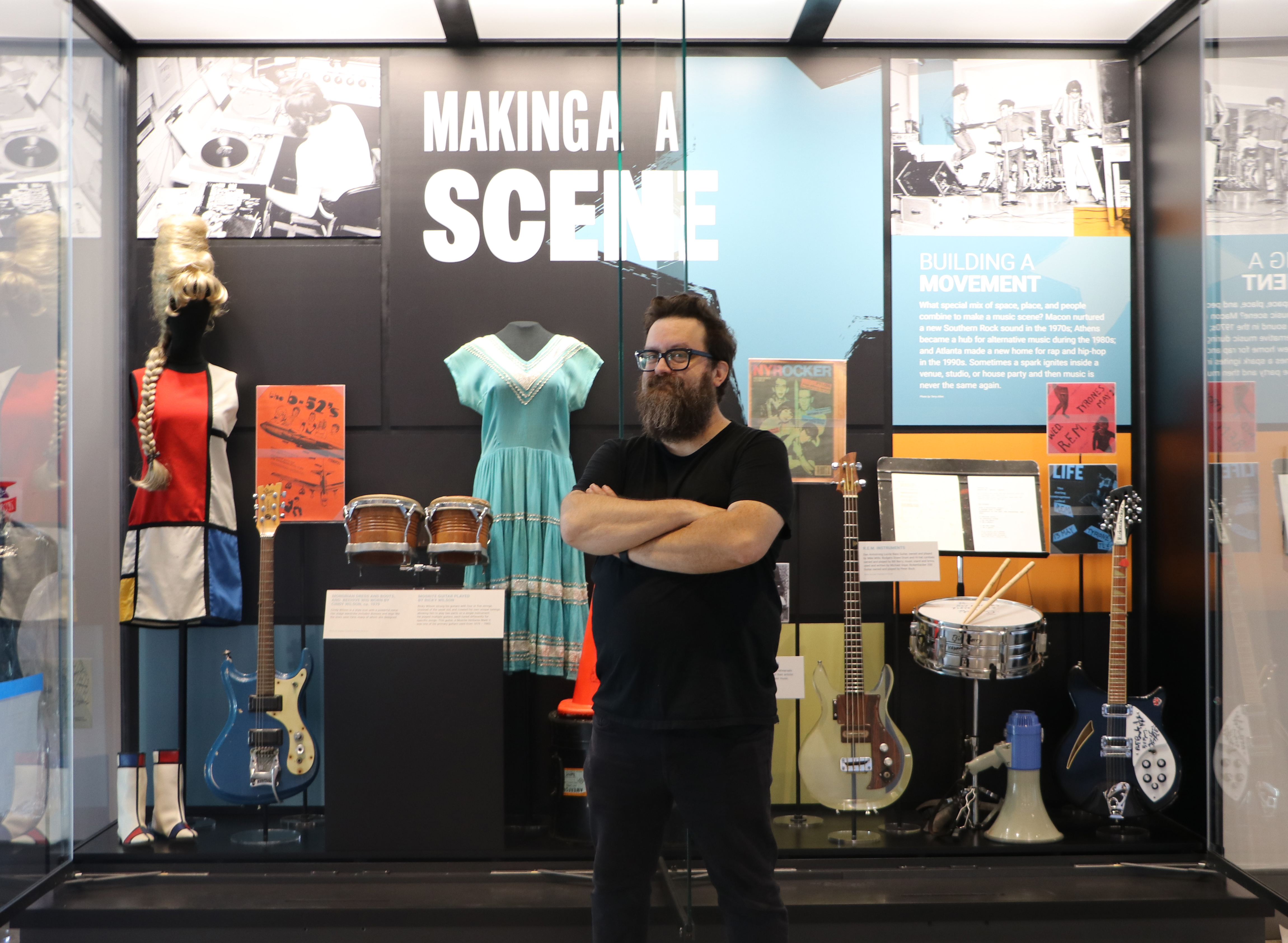 Curator Ryan Lewis posed in front of a display of Georgia musicians' clothes and instruments