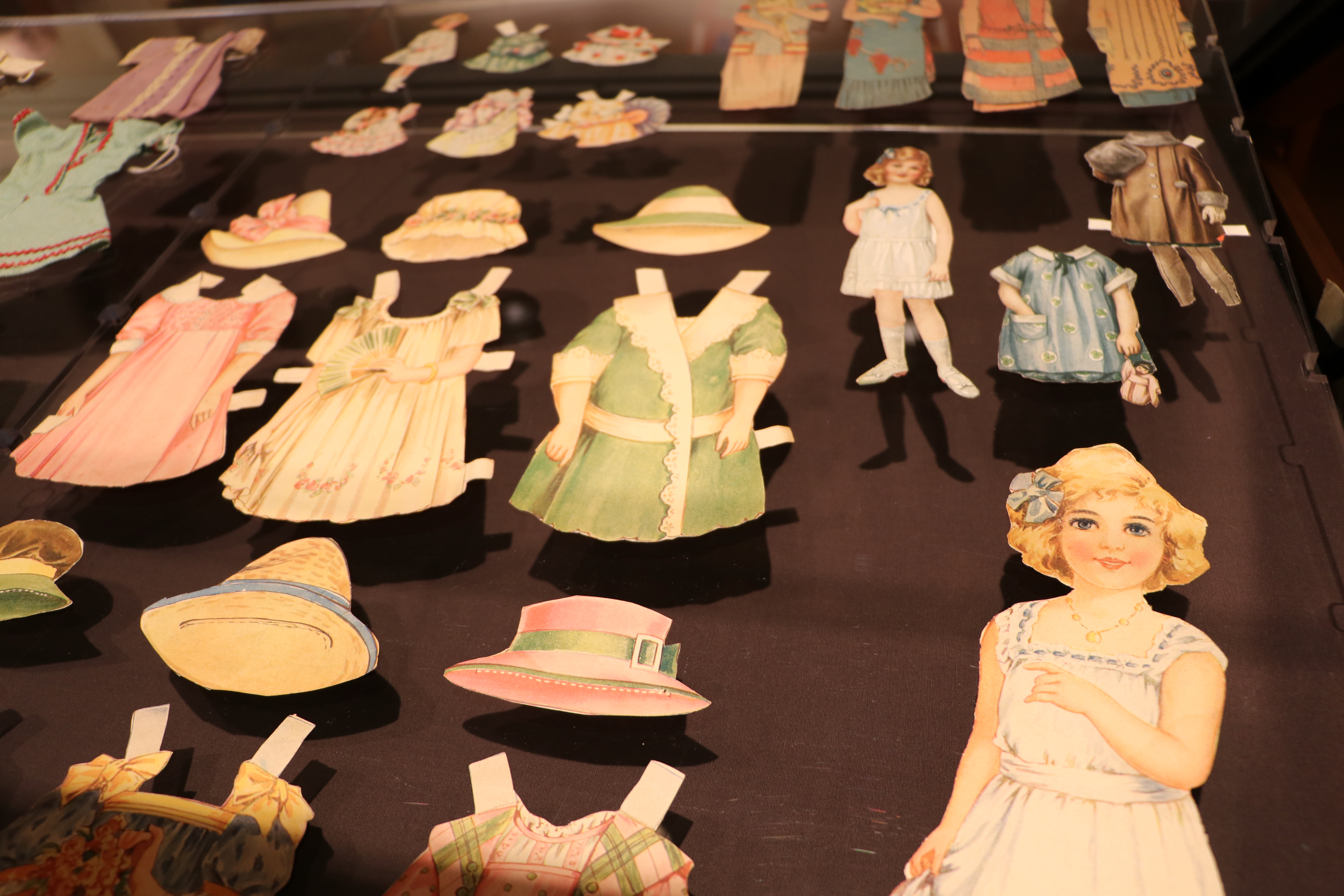 paper dolls and clothing in an exhibit case