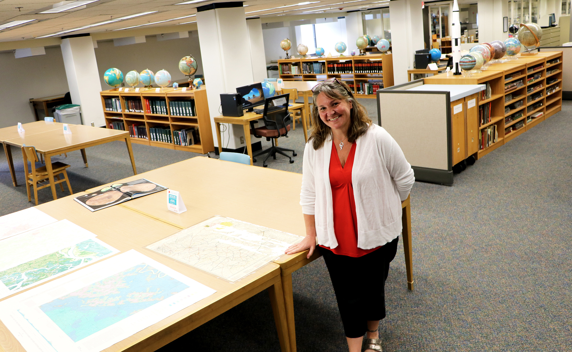 Valerie Glenn poses in front of globes and tables in the Map and Government Information Library at UGA