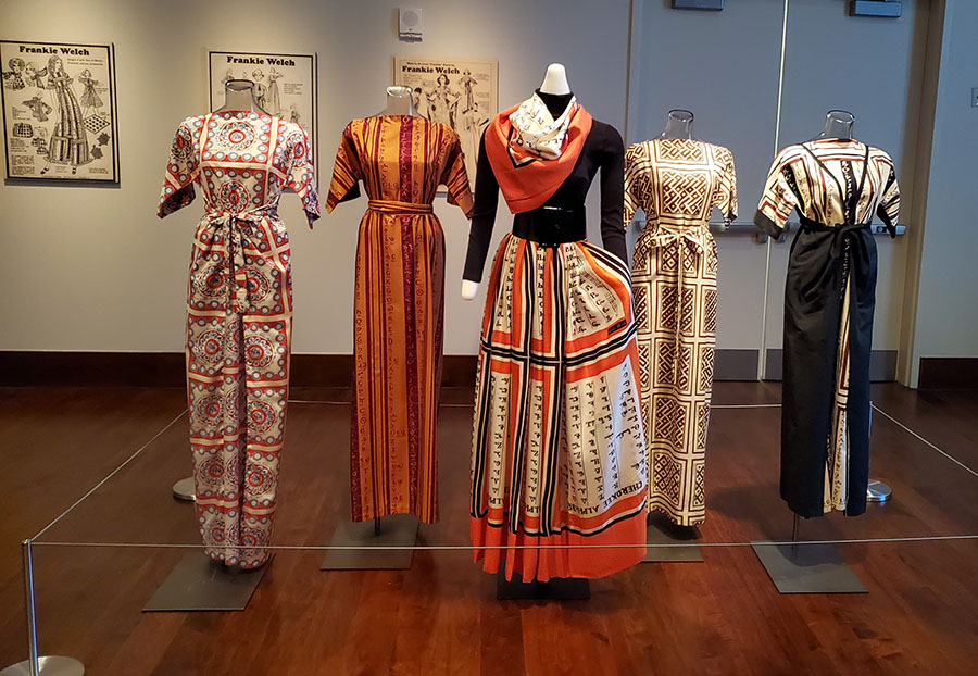 Mannequins wearing Welch-designed dresses in oranges, black and white, with African prints.