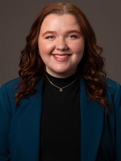 Woman with jacket and reddish wavy hair smiling